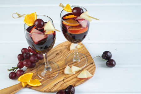Two glasses of sangria on a white wooden base. Traditional Spanish drink with fruit decoration. Copy space.の写真素材