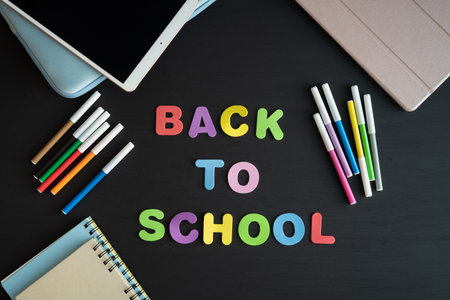 School materials with the phrase BACK TO SCHOOL on a black background. Copy space.