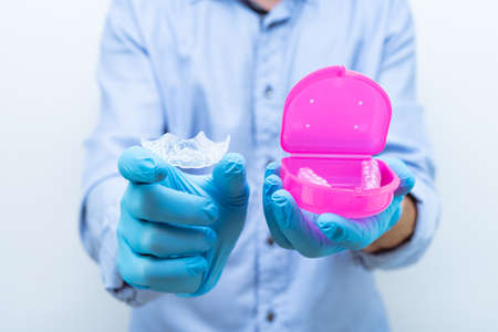 Dentist showing a dental splint with a pink protective box in the other hand. Copy space.
