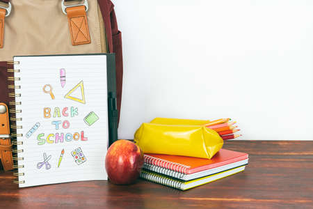 Notebook with back to school drawing. Backpack and school supplies with apple on white background. Copy spaceの写真素材