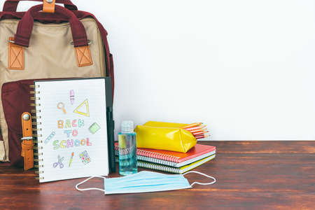 Notebook with back to school drawing. Backpack and school material with mask and gel. Copy spaceの写真素材