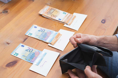 Man showing empty wallet after dividing all the money for monthly expenses. Copy space. Economy and crisis concept.の写真素材