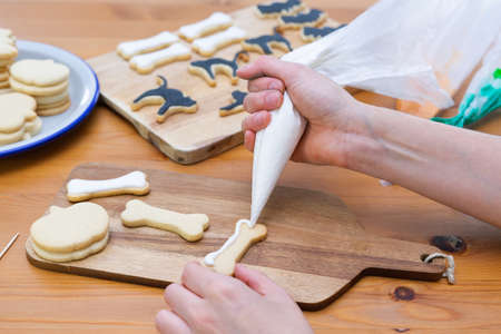 Womans hand decorating cookies for Halloween with piping bag. Copy space. Pastry.