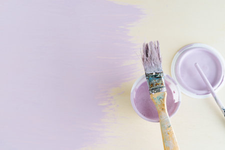 Mauve paint pot and brush on yellow background. Copy space.の写真素材