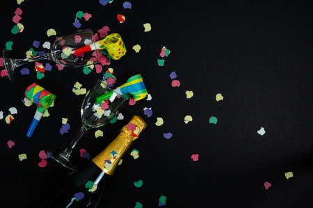 New Years Eve and New Years Eve celebrations. Black background. Copy space. Noise maker and bottle...
