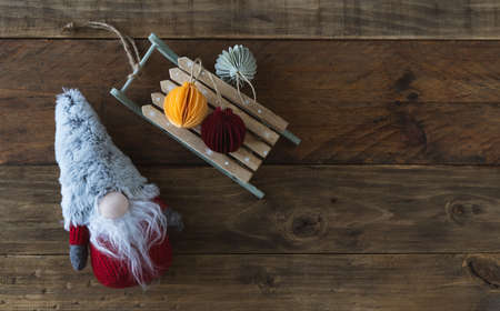 Christmas gnome with handmade paper spheres and sleigh. Wooden background. Copy space. Top view.