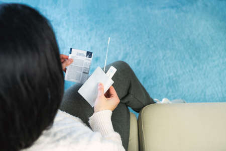 Seated woman reading antigen test instructions for covid 19 test. Copy space. Coronavirus concept.