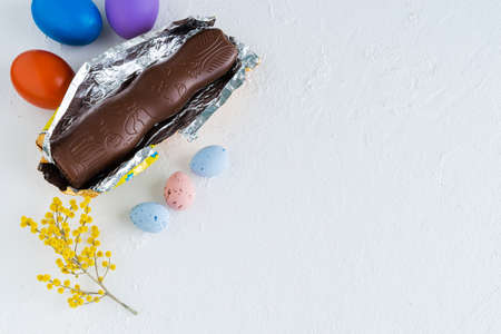 Easter eggs and chocolate bunny on white background with yellow flower decorations. Top view. Copyspace.の写真素材