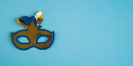Carnival mask with feathers on blue background. Copyspace.