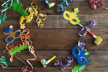 Carnival decoration on rustic wooden background with copy space in the center. Masks with ribbons and other carnival elements.の写真素材