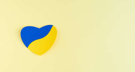 Heart cut out of paper with Ukrainian flag colors on yellow background. Copyspace.の写真素材