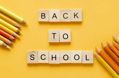 Back to class. Colored pencils and letters in wooden cubes BACK TO SCHOOL on yellow background. Copy space. Topview.の写真素材