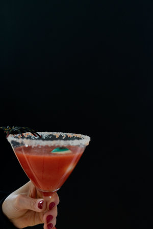 Woman's hand holds scary red cocktail with Halloween decoration on black background. Copyspace. Vertical photos.の写真素材