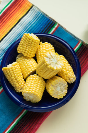 Blue bowl with pieces of cob on white background with decorative fabric. Copy space. Topview.
