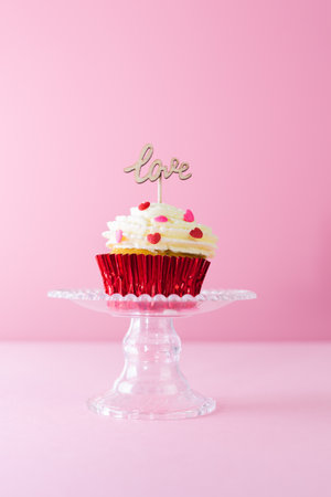 Valentine's Day. A cupcake with cream and red topping decoration with a wooden sign with the word...
