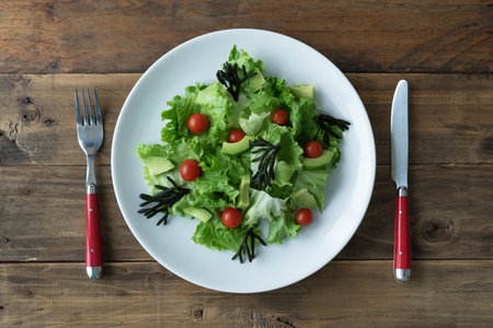 White plate of mixed salad with seaweed, tomatoes, lettuce and avocado. Wood background. Copyspace. top view.の写真素材