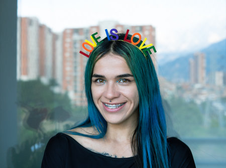 Young woman with braces in smiling with gay themed headband and blue hair. LOVE IS LOVE. Copyspace.の写真素材