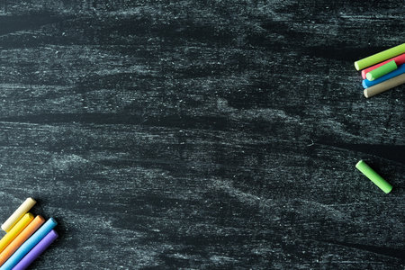 Dark background with texture and colored chalk on the sides. Free space in the center of the photo. Back to class.の写真素材