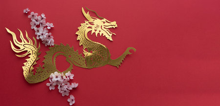 Chinese New Year. Dragon cut out in gilt paper with plum blossom decoration on red background. Copy space. Top view.の写真素材