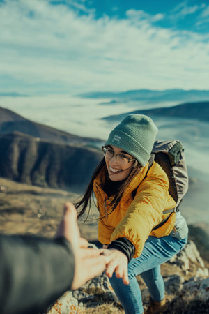 People helping each other hike up a mountain at sunrise.の写真素材