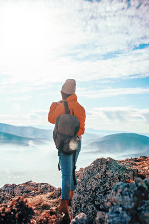 Cheering woman backpacker enjoy the view on sunrise mountain top cliff edge