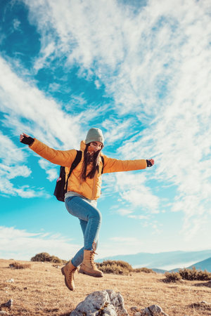 Cheering woman backpacker enjoy the view on sunrise mountain top cliff edgeの写真素材