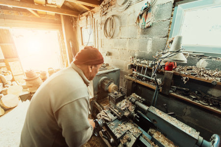 A senior man procesing wood on a lathe and making wooden dishes in the workshopの写真素材