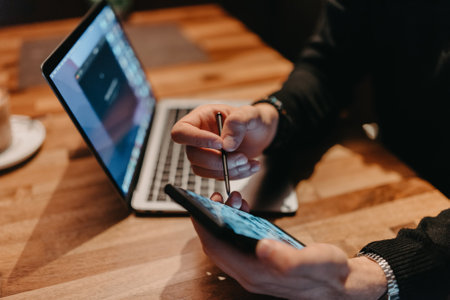 Happy young businessman working on a laptop and smartphone in a cafeの写真素材