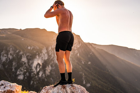 An athlete rests on top of a mountain after exhausting running training.の写真素材