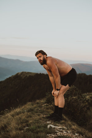 An athlete rests on top of a mountain after exhausting running training.の写真素材
