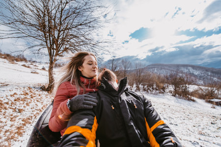 Couple enjoying while driving quad bike on top of mountain at winter timeの写真素材