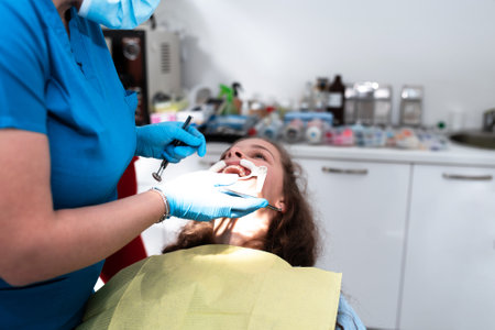 Dentist appointment at a dental clinic, placing braces locks on the teeth and pulling the archwire to fix itの写真素材
