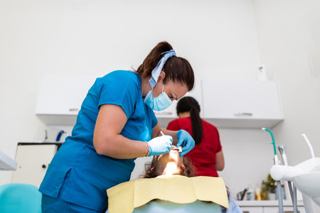 Dentist appointment at a dental clinic, placing braces locks on the teeth and pulling the archwire to fix itの写真素材