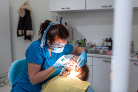Dentist appointment at a dental clinic, placing braces locks on the teeth and pulling the archwire to fix itの写真素材