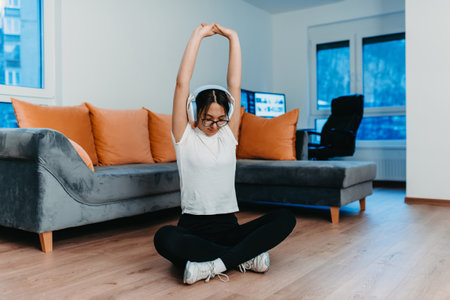 A woman stretching in her apartment during early morning after training , reflecting her dedication to a healthy lifestyle. This moment highlights the importance of regular exercise and self-care, even in the comfort of ones own homeの写真素材