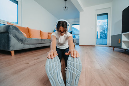 A woman stretching in her apartment during early morning after training , reflecting her dedication to a healthy lifestyle. This moment highlights the importance of regular exercise and self-care, even in the comfort of ones own homeの写真素材