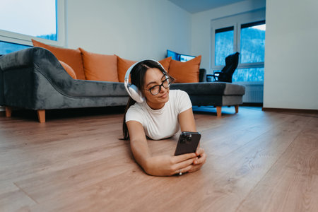 A woman doing home workout with headphones and smartphone for a video call. Reflects modern lifestyle, blending technology, health, and connectivity for holistic well-being.の写真素材
