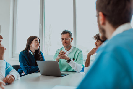 A group of multiethnic medical professionals including doctors, surgeons, and nurses are gathered in a hospital setting discussing patient care and using modern technology to address challenges in the medical field.の写真素材