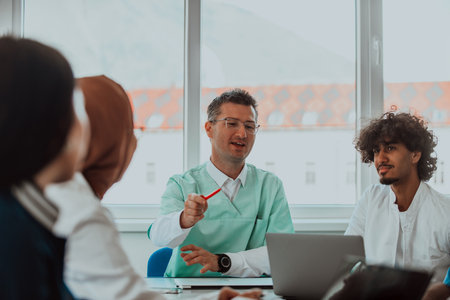 A group of multiethnic medical professionals including doctors, surgeons, and nurses are gathered in a hospital setting discussing patient care and using modern technology to address challenges in the medical field.の写真素材