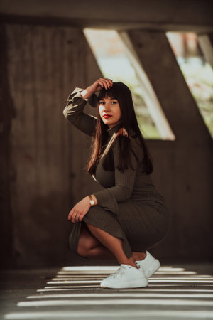 A confident and stylish plus-size woman posing by a modern building in an olive green dress, radiating beauty, empowerment, and self-love.の写真素材