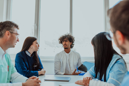 A group of multiethnic medical professionals including doctors, surgeons, and nurses are gathered in a hospital setting discussing patient care and using modern technology to address challenges in the medical field.の写真素材