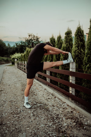 Athlete performing leg stretching exercises after a run in a natural environment. Fitness themed photograph showcasing physical activity flexibility and health.の写真素材