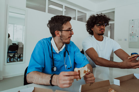 African American doctor taking a break from work in a modern medical office, enjoys pizza with colleagues, fostering a sense of camaraderie and relaxation amidst their busy healthcare profession.の写真素材