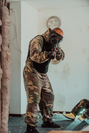 Paintball player in mask who is aiming in opponents at paintball arena. Selective focusの写真素材
