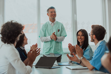 A team of doctors and a medical nurse applauding their colleague after a presentation in a meeting roomの写真素材
