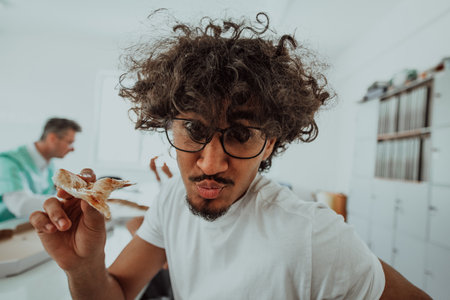 African American doctor taking a break from work in a modern medical office, enjoys pizza with colleagues, fostering a sense of camaraderie and relaxation amidst their busy healthcare profession.の写真素材