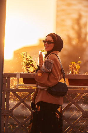 A hijab woman in stylish sunglasses and an elegant French outfit, walking through the city at...