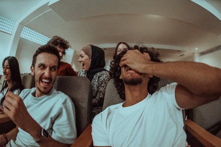 omedy film, with smiles oIn a cinema a diverse group of teenagers is gathered, watching a cn their faces, enjoying the shared laughter and the joy of being together.の写真素材