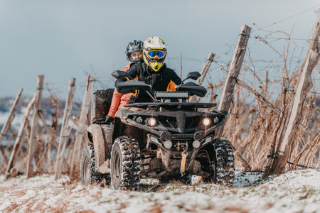 A young adventurous couple embraces the joy of love and thrill as they ride an ATV Quad through the snowy mountainous terrainの写真素材