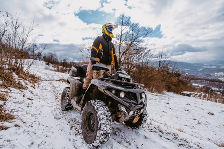 A young adventurous couple embraces the joy of love and thrill as they ride an ATV Quad through the snowy mountainous terrainの写真素材